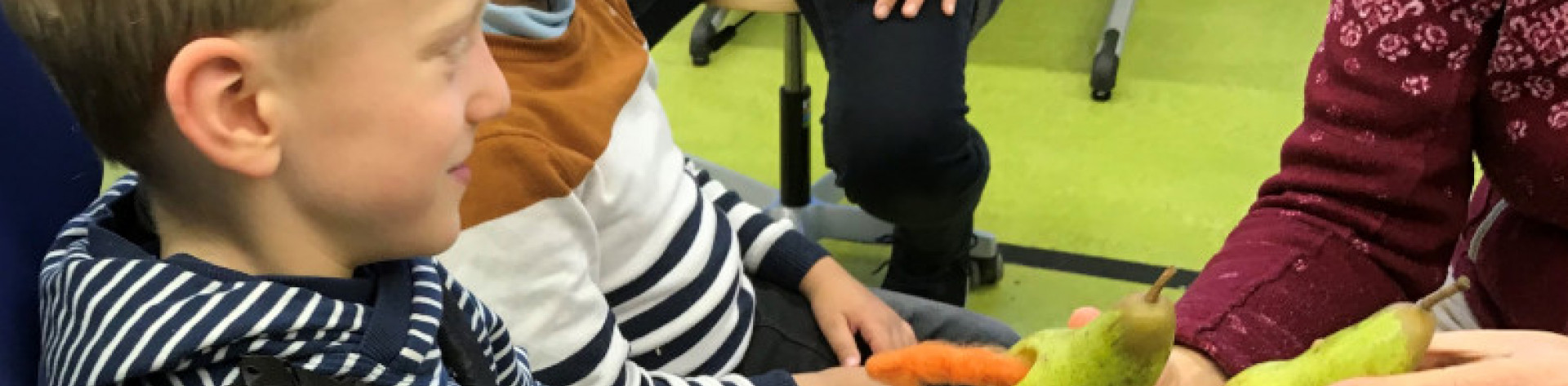 Lehrerin zeigt Kindern Birnen mit Raupe Nimmersatt