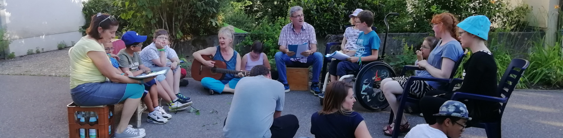 Internatsgruppe sitzt am Lagerfeuer und singt zur Gitarre